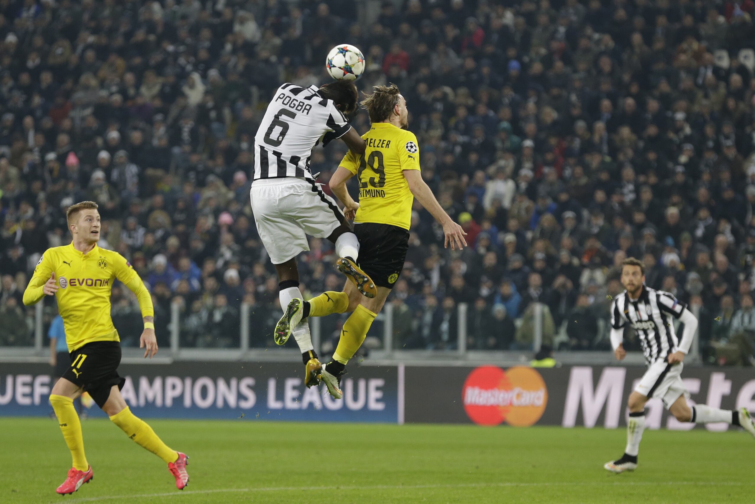 Juventus' Paul Pogba and Dortmund's Marcel Schmelzer, right, jump for the ball during the Champions League round of 16 first leg soccer match between Juventus and Borussia Dortmund at the Juventus stadium in Turin, Italy, Tuesday, Feb. 24, 2015. (AP Photo/Antonio Calanni)