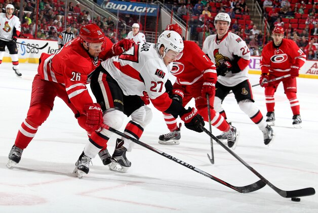 RALEIGH, NC - MARCH 17: John-Michael Liles #26  of the Carolina Hurricanes reaches for the puck around Curtis Lazar #27 of the Ottawa Senators during their NHL game at PNC Arena on March 17, 2015 in Raleigh, North Carolina.  (Photo by Gregg Forwerck/NHLI via Getty Images)