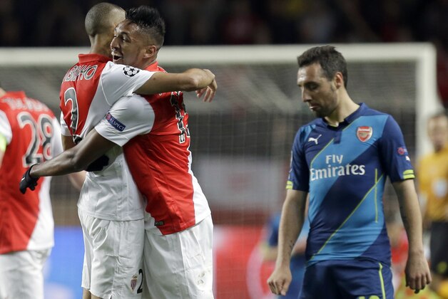 Monaco players celebrate after the final whistle while Arsenal's Santi Cazorla leaves the pitch after their Champions League round of 16 second leg soccer match between Monaco and Arsenal at Louis II stadium in Monaco, Tuesday, March 17, 2015. Monaco withstood Arsenal's onslaught to reach the quarterfinals of the Champions League despite a 2-0 home defeat on Tuesday, advancing on the away goals rule after drawing 3-3 on aggregate.  (AP Photo/Lionel Cironneau)