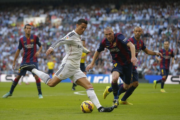 Real Madrid's Cristiano Ronaldo, centre left, in action with Barcelona’s Jeremy Mathieu, centre right, during a Spanish La Liga soccer match between Real Madrid and FC Barcelona at the Santiago Bernabeu stadium in Madrid, Spain, Saturday, Oct. 25, 2014. (AP Photo/Andres Kudacki)