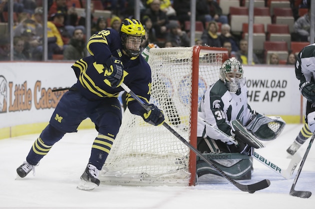 Michigan center Dylan Larkin (19) tries a wrap around shot on Michigan State goalie Jake Hildebrand (30) during the first period of an NCAA college hockey game, Friday, Jan. 30, 2015 in Detroit. (AP Photo/Carlos Osorio)