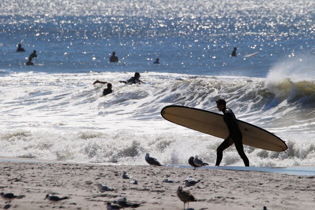 LONG BEACH, NY - AUGUST 28:  A surfer prepares to enter four to six foot swells off the Atlantic Ocean on August 28, 2014 in Long Beach, New York. Hurricane Cristobal is churning up larger than normal waves along the eastern coast of the United States.  (Photo by Bruce Bennett/Getty Images)