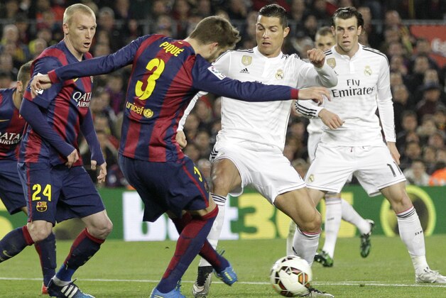 Barcelona's Jeremy Mathieu, second left, and Barcelona's Gerard Pique, center, defend as Real Madrid's Cristiano Ronaldo, center right, plays the ball during a Spanish La Liga soccer match between FC Barcelona and Real Madrid at Camp Nou stadium, in Barcelona, Spain, Sunday, March 22, 2015. (AP Photo/Emilio Morenatti)