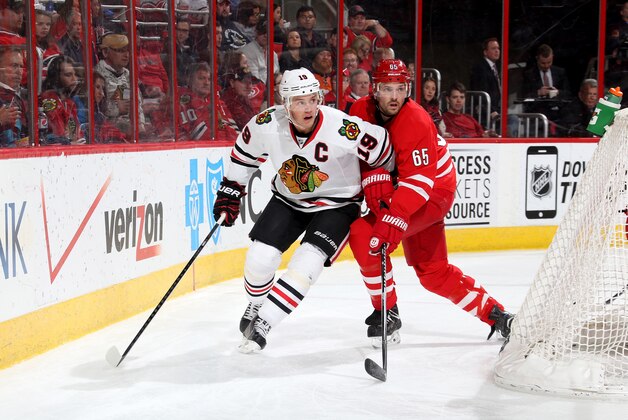RALEIGH, NC - MARCH 23: Ron Hainsey #65 of the Carolina Hurricanes and Jonathan Toews #19 of the Chicago Blackhawks battle behind the net during their NHL game at PNC Arena on March 23, 2015 in Raleigh, North Carolina.  (Photo by Gregg Forwerck/NHLI via Getty Images)