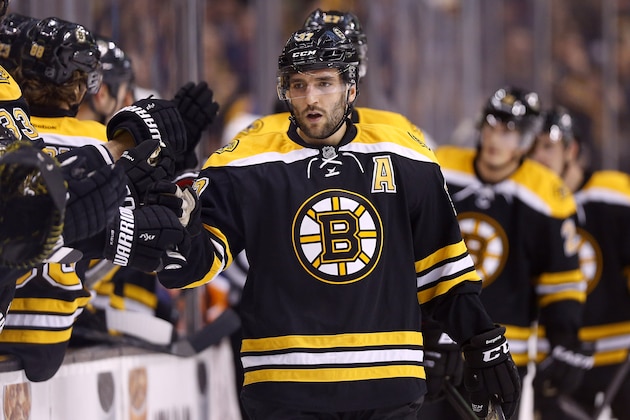 Boston Bruins' Patrice Bergeron is congratulated at the bench after scoring against the New York Islanders during the first period of an NHL hockey game in Boston, Saturday, Feb. 7, 2015. (AP Photo/Winslow Townson)