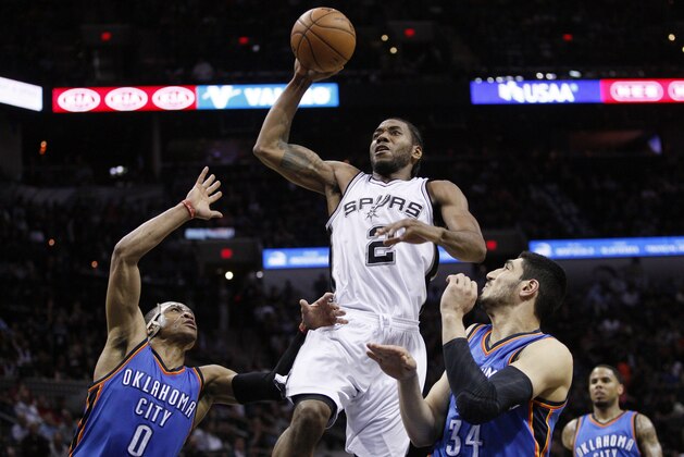Mar 25, 2015; San Antonio, TX, USA; San Antonio Spurs small forward Kawhi Leonard (2) dunks the ball as Oklahoma City Thunder point guard Russell Westbrook (0) and center Enes Kanter (34) defend during the first half at AT&T Center. Mandatory Credit: Soobum Im-USA TODAY Sports