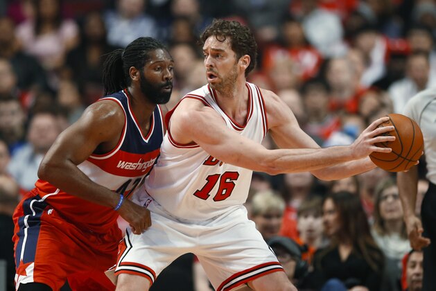 El español Pau Gasol, de los Bulls de Chicago, aleja el balón del brasileño Nené, de los Wizards de Washington, en el partido del martes 3 de marzo de 2015 (AP Foto/Kamil Krzaczynski)