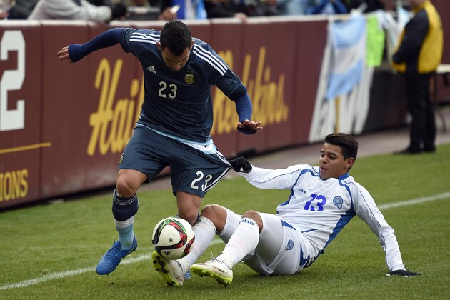 El Salvador's Alexander Larin (13) pulls on the shorts of Carlos Tevez (23) during the first half of an international friendly, Saturday, March 28, 2015, in Landover, Md. (AP Photo/Nick Wass)