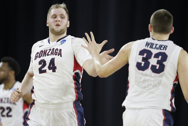 Gonzaga's Przemek Karnowski (24) is congratulated by teammate Kyle Wiltjer (33) during the second half of a college basketball regional semifinal game in the NCAA Tournament against UCLA, Friday, March 27, 2015, in Houston. (AP Photo/Charlie Riedel)
