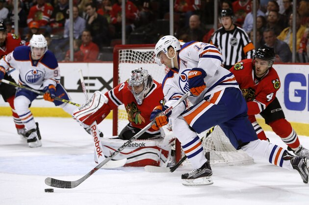 Edmonton Oilers right wing Jordan Eberle (14) is unable to shoot against Chicago Blackhawks goalie Corey Crawford (50) as Blackhawks' Niklas Hjalmarsson (4) also defends during the first period of an NHL hockey game Friday, March 6, 2015, in Chicago. (AP Photo/Charles Rex Arbogast)
