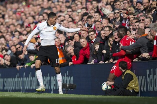 Manchester United's Chris Smalling, left, points to Liverpool's Mario Balotelli after a collision during the English Premier League soccer match between Liverpool and Manchester United at Anfield Stadium, Liverpool, England, Sunday, March 22, 2015. (AP Photo/Jon Super)