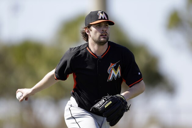 Miami Marlins pitcher Aaron Crow tosses to first as part of a fielding drill during spring training baseball practice Friday, Feb. 20, 2015, in Jupiter, Fla. (AP Photo/Jeff Roberson)