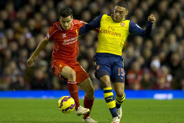 Liverpool's  Philippe Coutinho, left, fights for the ball against Arsenal's Alex Oxlade-Chamberlain during the English Premier League soccer match between Liverpool and Arsenal at Anfield Stadium, Liverpool, England, Sunday Dec. 21, 2014. (AP Photo/Jon Super)
