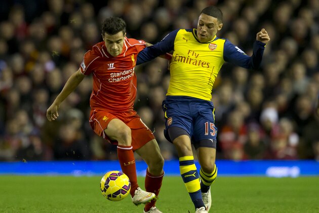 Liverpool's  Philippe Coutinho, left, fights for the ball against Arsenal's Alex Oxlade-Chamberlain during the English Premier League soccer match between Liverpool and Arsenal at Anfield Stadium, Liverpool, England, Sunday Dec. 21, 2014. (AP Photo/Jon Super)
