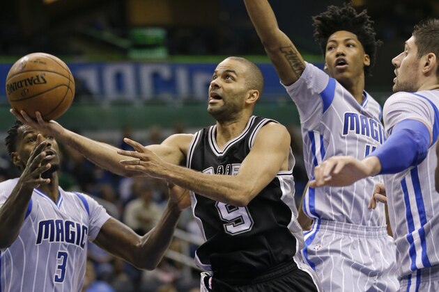 San Antonio Spurs' Tony Parker, center, goes in for a shot as he gets open between Orlando Magic's Dewayne Dedmon (3), Elfrid Payton, second from right, and Nikola Vucevic, right, during the second half of an NBA basketball game, Wednesday, April 1, 2015, in Orlando, Fla. San Antonio won 103-91. (AP Photo/John Raoux)