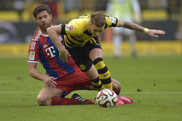 Bayern’s Xabi Alonso, left, and Dortmund's Marco Reus challenge for the ball during the German Bundesliga soccer match between Borussia Dortmund and Bayern Munich in Dortmund, Germany, Saturday, April 4, 2015.  (AP Photo/Martin Meissner)