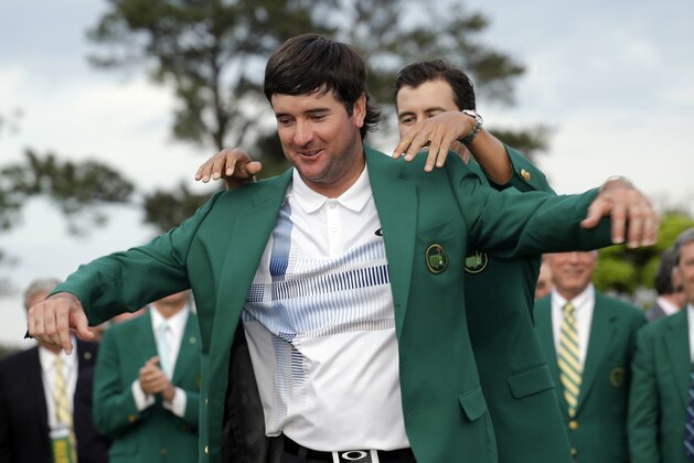Defending Masters' champion Adam Scott, of Australia, helps Bubba Watson, left, with his green jacket after winning the Masters golf tournament Sunday, April 13, 2014, in Augusta, Ga. (AP Photo/David J. Phillip)