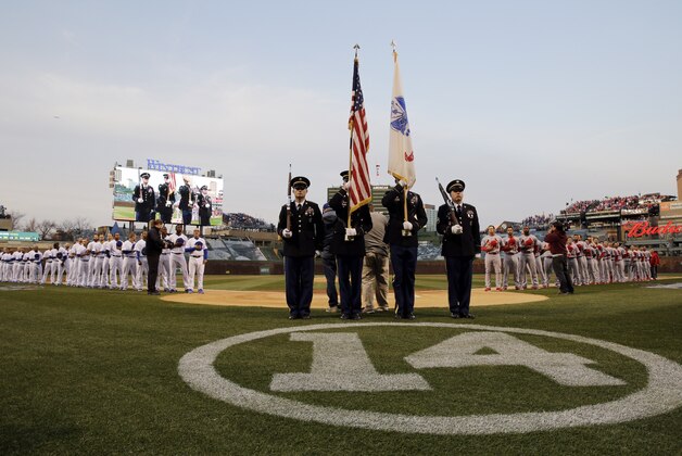 Chicago Cubs players and St. Louis Cardinals listen to national anthem before a Major League Baseball season-opening game in Chicago, Sunday, April 5, 2015. (AP Photo/Nam Y. Huh)