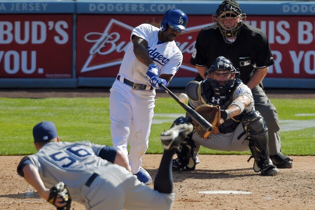 Los Angeles Dodgers' Jimmy Rollins, second from left, hits a three-run home run as San Diego Padres relief pitcher Shawn Kelley, left, pitches and catcher Derek Norris, second from right, watches along with home plate umpire Brian Gorman during the eighth inning of an opening day baseball game, Monday, April 6, 2015, in Los Angeles. (AP Photo/Mark J. Terrill)
