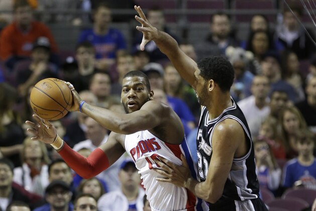 Detroit Pistons forward Greg Monroe (10) passes the ball as he is defended by San Antonio Spurs forward Tim Duncan (21) during the first half of an NBA basketball game in Auburn Hills, Mich., Monday, Feb. 10, 2014. (AP Photo/Carlos Osorio)