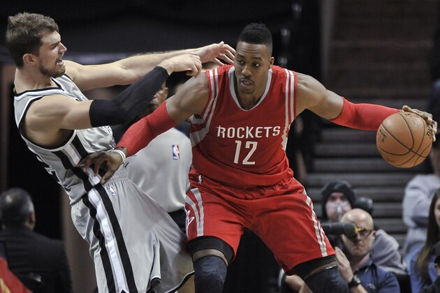 Houston Rockets center Dwight Howard, right, makes contact with San Antonio Spurs forward Tiago Splitter, of Brazil, during the second half of an NBA basketball game, Sunday, Dec. 28, 2014, in San Antonio. San Antonio won 110-106. (AP Photo/Darren Abate)