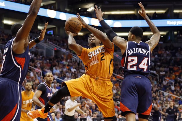Phoenix Suns' Eric Bledsoe (2) shoots between Atlanta Hawks' Kent Bazemore (24) and Elton Brand during the second half of an NBA basketball game, Friday, March 13, 2015, in Phoenix. The Hawks won 96-87. (AP Photo/Matt York)