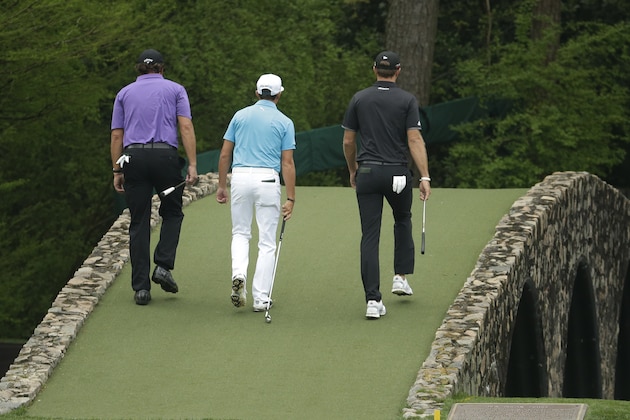 From left, Phil Mickelson, Rickie Fowler and Dustin Johnson walk across the Ben Hogan Bridge during a practice round for the Masters golf tournament Tuesday, April 7, 2015, in Augusta, Ga. (AP Photo/Charlie Riedel)