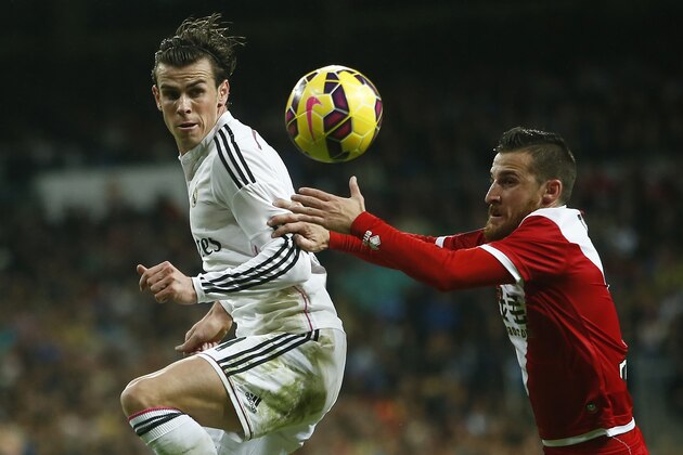 Real Madrid's Gareth Bale, left, in action with Rayo's Tito during a Spanish La Liga soccer match between Rayo Vallecano and Real Madrid at the Santiago Bernabeu stadium in Madrid, Spain, Saturday, Nov. 8, 2014. (AP Photo/Andres Kudacki)