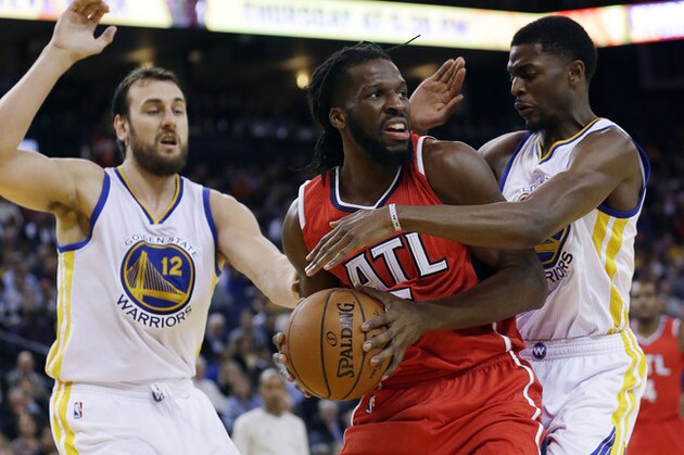 Atlanta Hawks' DeMarre Carroll, center, is defended by Golden State Warriors' Justin Holiday, right, and Andrew Bogut (12) during the first half of an NBA basketball game Wednesday, March 18, 2015, in Oakland, Calif. (AP Photo/Marcio Jose Sanchez)