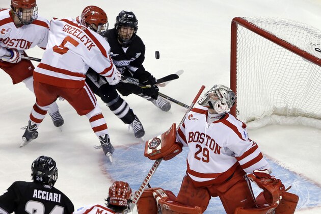 Boston University goalie Matt O'Connor (29) watches the puck deflect up as Providence forward Shane Luke (20) struggles for position against Boston U defenseman Matt Grzelcyk (5) during the first period of the NCAA men's Frozen Four hockey championship game in Boston, Saturday, April 11, 2015. (AP Photo/Elise Amendola)