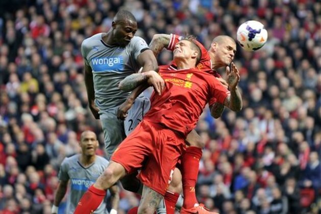 Liverpool's Daniel Agger, center, and Martin Skrtel, right, jump for the ball with Newcastle United's Shola Ameobi during an English Premier League soccer match at Anfield in Liverpool, England, Sunday May 11, 2014. (AP Photo/Clint Hughes)