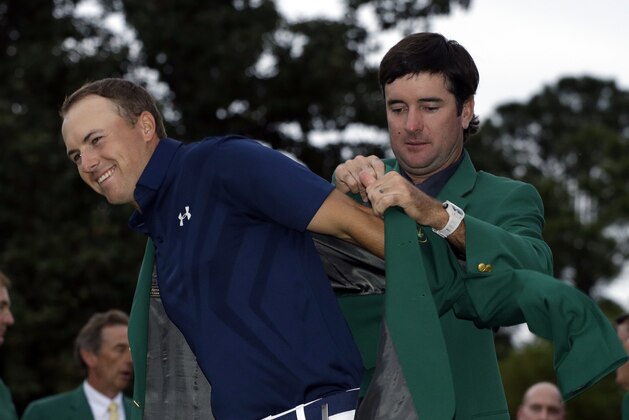 Bubba Watson helps Jordan Spieth put on his green jacket for the second time after winning the Masters golf tournament Sunday, April 12, 2015, in Augusta, Ga. (AP Photo/Darron Cummings)