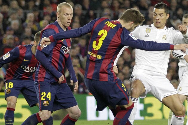 Barcelona's Jeremy Mathieu, second left, and Barcelona's Gerard Pique, center, defend as Real Madrid's Cristiano Ronaldo, center right, plays the ball during a Spanish La Liga soccer match between FC Barcelona and Real Madrid at Camp Nou stadium, in Barcelona, Spain, Sunday, March 22, 2015. (AP Photo/Emilio Morenatti)