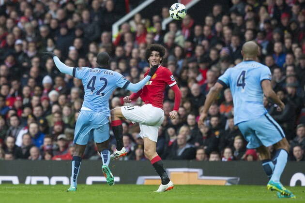 Manchester United's Marouane Fellaini, centre, fights for the ball against Manchester City's Yaya Toure, left, as Vincent Kompany looks on during the English Premier League soccer match between Manchester United and Manchester City at Old Trafford Stadium, Manchester, England, Sunday, April 12, 2015. (AP Photo/Jon Super)