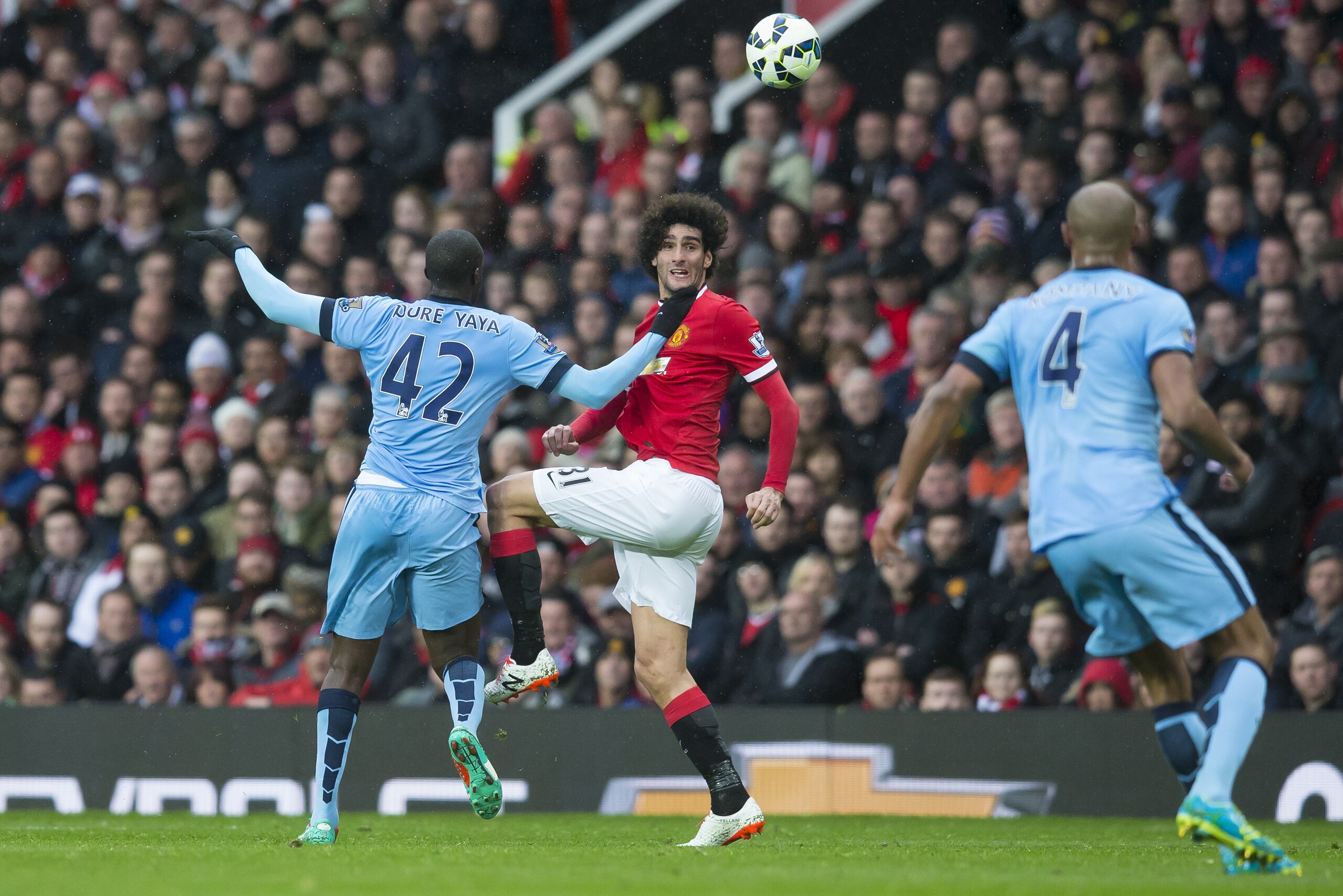Manchester United's Marouane Fellaini, centre, fights for the ball against Manchester City's Yaya Toure, left, as Vincent Kompany looks on during the English Premier League soccer match between Manchester United and Manchester City at Old Trafford Stadium, Manchester, England, Sunday, April 12, 2015. (AP Photo/Jon Super)