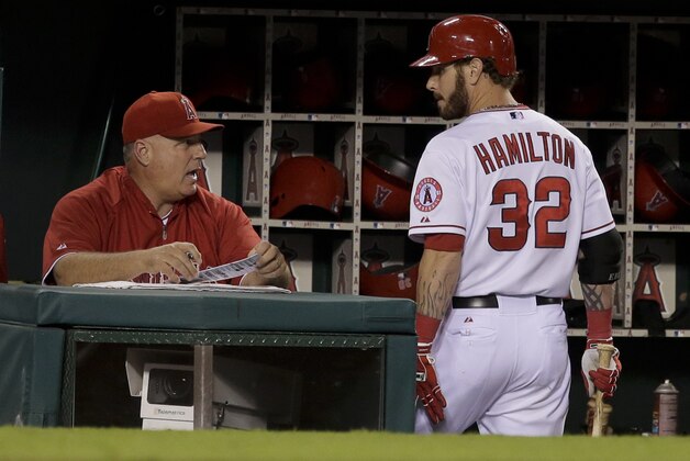 Los Angeles Angels manager Mike Scioscia, left, talks with Josh Hamilton after he struck out with two runners on base during the eighth inning of a baseball game against the Seattle Mariners in Anaheim, Calif., Friday, Sept. 20, 2013. (AP Photo/Chris Carlson)