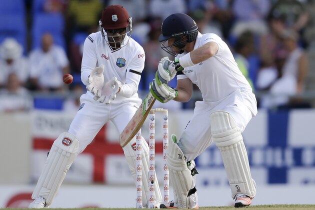 England's Ian Bell  hits a four off West Indies' Marlon Samuels to complete 102 runs during the opening day of their first cricket Test match at the Sir Vivian Richards Cricket Ground in Antigua, Antigua and Barbuda, Monday, April 13, 2015.  West Indies' wicket keeper Denesh Ramdin in in the back . (AP Photo/Ricardo Mazalan)