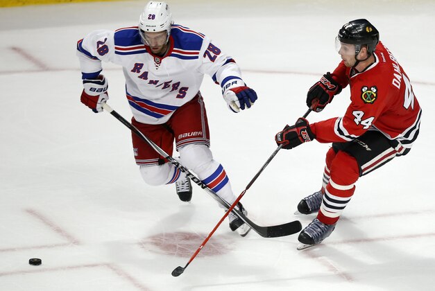New York Rangers center Dominic Moore (28) chases the puck with Chicago Blackhawks defenseman Klas Dahlbeck (44) during the third period of a preseason NHL hockey game on Friday, Sept. 26, 2014, in Chicago. The New York Rangers won 4-1. (AP Photo/Andrew A. Nelles)