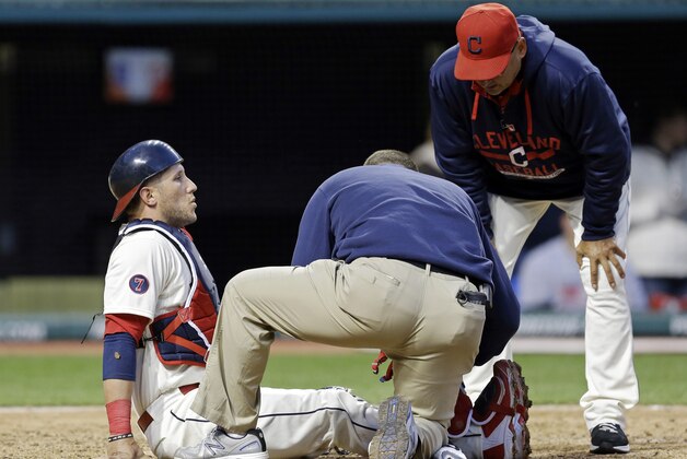 Cleveland Indians catcher Yan Gomes, left, is attended to by assistant trainer Jeff Desjardins as manager Terry Francona looks on, right, in the ninth inning of a baseball game against the Detroit Tigers Saturday, April 11, 2015, in Cleveland. Gomes was injured on a play at the plate in the 9-6 loss to the Tigers. (AP Photo/Mark Duncan)