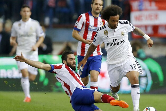 Atletico's Arda Turan, left, challenges Real Madrid's Marcelo, right, during the Champions League quarterfinal, first leg soccer match between Atletico de Madrid and Real Madrid at the Vicente Calderon stadium in Madrid, Spain, Tuesday, April 14, 2015. (AP Photo/Daniel Ochoa de Olza)