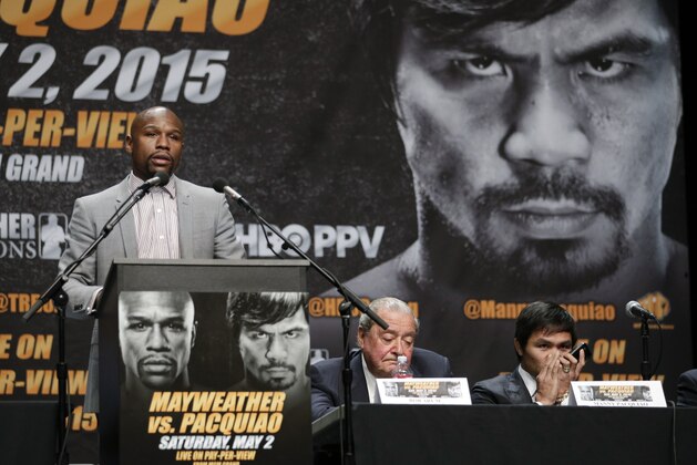 Floyd Mayweather Jr., left, speaks as Manny Pacquiao, right, of the Philippines, speaks into his phone while sitting next to promoter Bob Arum during a news conference, Wednesday, March 11, 2015, in Los Angeles. Mayweather and Pacquiao are scheduled to fight in Las Vegas on May 2. (AP Photo/Jae C. Hong)