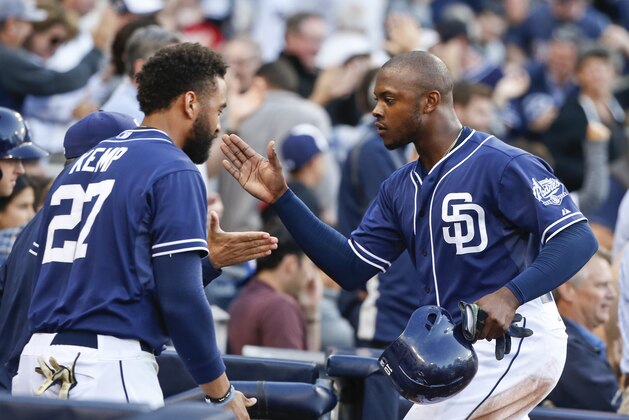 San Diego Padres' Justin Upton, right, is congratulated at the dugout by Matt Kemp and others after scoring against the San Francisco Giants during the third inning of a baseball game Saturday, April 11, 2015, in San Diego. (AP Photo/Lenny Ignelzi)