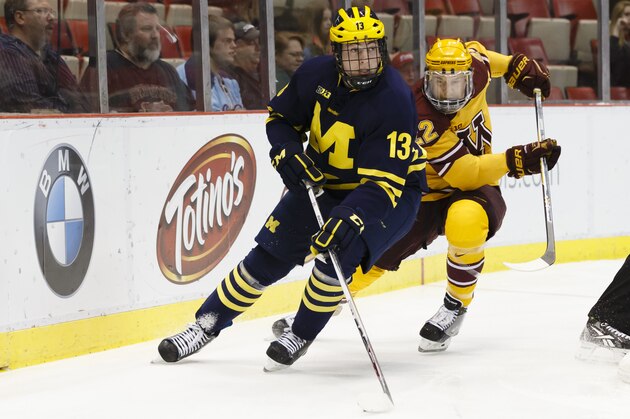 Michigan's Zach Werenski (13) skates with the puck near Minnesota's Travis Boyd in the first period during an NCAA college hockey game in the Big Ten Conference tournament Saturday, March 21, 2015, in Detroit. (AP Photo/Rick Osentoski)