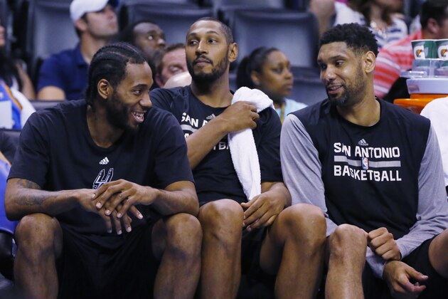 San Antonio Spurs' Kawhi Leonard, left, smiles as he talks on the bench with teammate Tim Duncan, right, during the fourth quarter of an NBA basketball game against the Oklahoma City Thunder in Oklahoma City, Tuesday, April 7, 2015. Boris Diaw is at center. San Antonio won 113-88. (AP Photo/Sue Ogrocki)