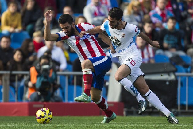 Atletico's Arda Turan, left, in action with Coruna's Pablo Insua, right, during a Spanish La Liga soccer match between Atletico and Deportivo Coruna at the Vicente Calderon stadium in Madrid, Spain, Sunday, Nov. 30, 2014. (AP Photo/Andres Kudacki)