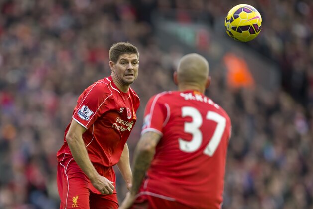 Liverpool's Steven Gerrard, left, passes the ball to teammate Martin Skrtel during the English Premier League soccer match between Liverpool and Chelsea at Anfield Stadium, Liverpool, England, Saturday, Nov. 8, 2014. (AP Photo/Jon Super)