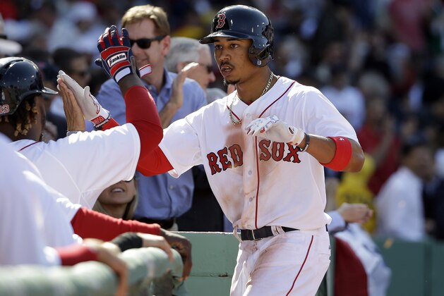 Boston Red Sox's Mookie Betts, right, is welcomed to the dugout after hitting a three-run home run off a pitch by Washington Nationals pitcher Jordan Zimmermann in the second inning of a baseball game, Monday, April 13, 2015, in Boston. (AP Photo/Steven Senne)
