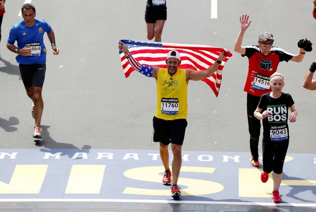 Apr 21, 2014; Boston, MA, USA; Frank Fumich of Arlington, VA holds an American flag as he crosses the finish line during the 2014 Boston Marathon. Mandatory Credit: Greg M. Cooper-USA TODAY Sports
