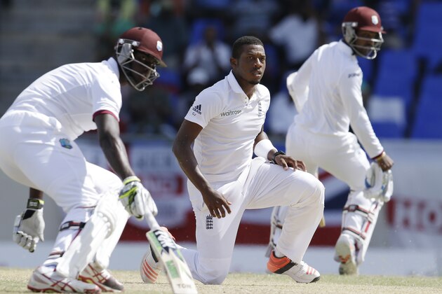England's bowler Chris Jordan kneels as West Indies' Jason Holder, left, and Denesh Ramdin, turn to run, during the last day of their first cricket Test match at the Sir Vivian Richards Cricket Ground in Antigua, Antigua and Barbuda, Friday, April 17, 2015.  (AP Photo/Ricardo Mazalan)