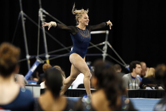 Florida teammates, foreground, watch as Samantha Peszek runs through her floor exercise routine during the NCAA women's Gymnastics Championships Friday, April 17, 2015, in Fort Worth, Texas. (AP Photo/Tony Gutierrez)